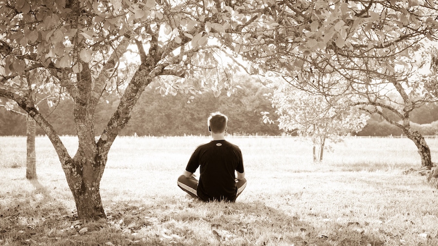 man meditating in a park during the day